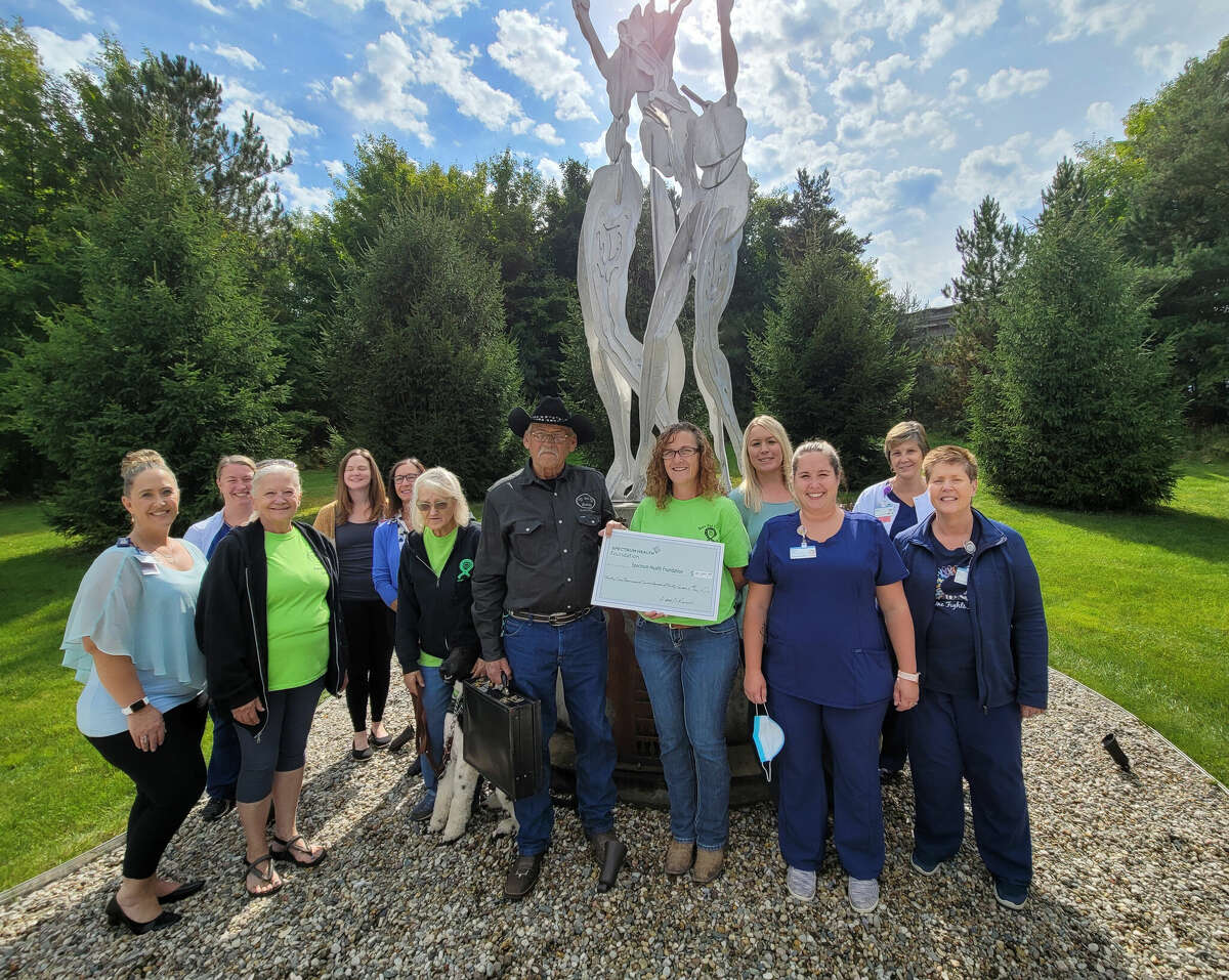 Don Beach, owner and trail boss at D Bar D Ranch, at center, along with other family members and friends presented team members at the cancer center with event proceeds Sept. 20.