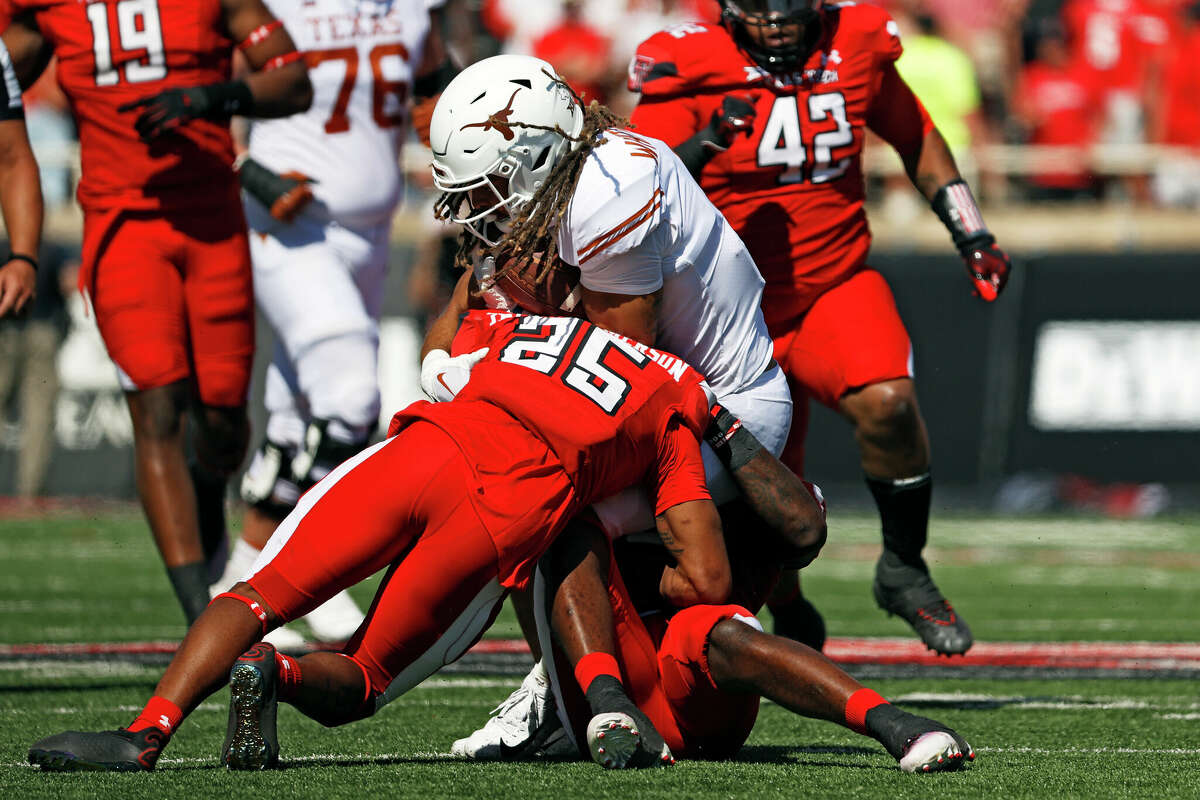 Texas Tech's Dadrion Taylor-Demerson (25) and Jesiah Pierre (8) tackle Texas' Jordan Whittington (4) during the first half of an NCAA college football game Saturday, Sept. 24, 2022, in Lubbock.