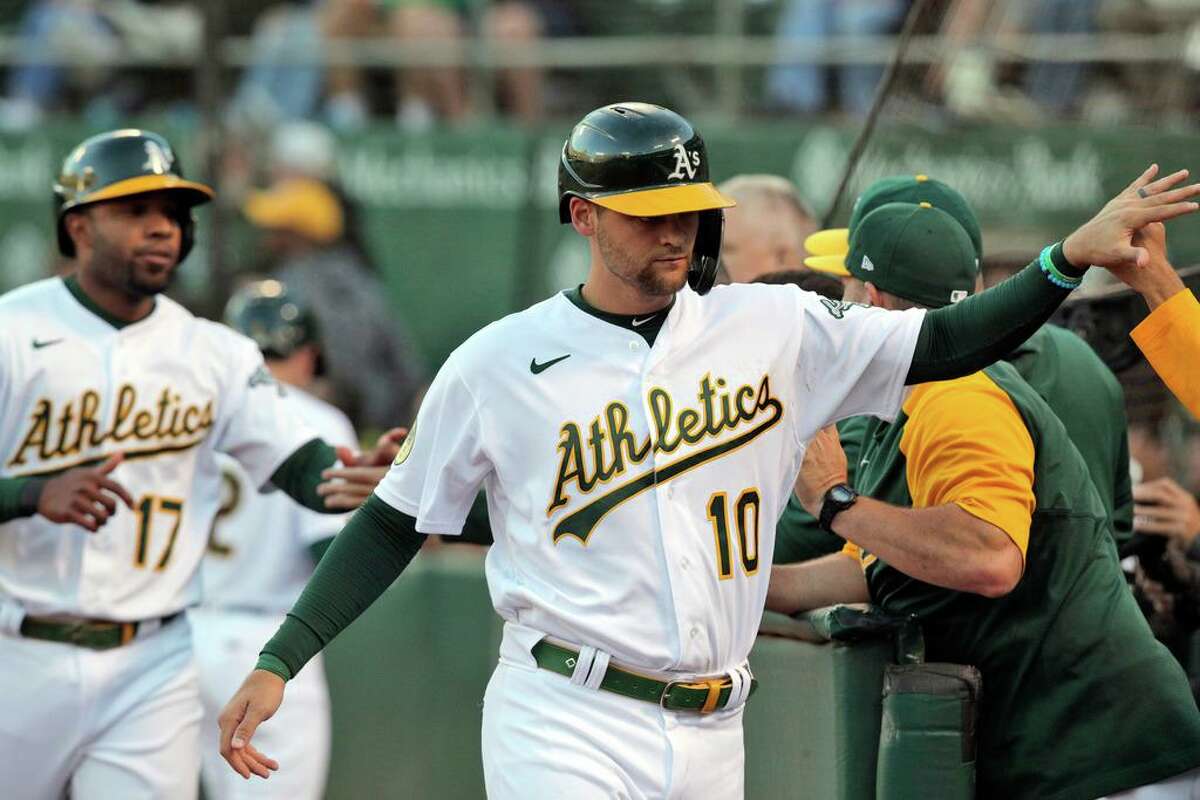 Chad PInder (10) and Elvis Andrus (17) high five teammates after scoring on a double by Tony Kemp (5) in the fourth inning as the Oakland Athletics played the Houston Astros at the Coliseum in Oakland, Calif., on Monday, July 25, 2022.