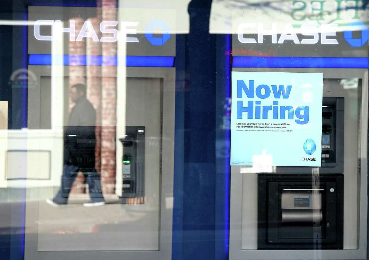 Gavin Newsom's new law requires employers to show pay range in job listings. A pedestrian walks by a "now hiring" sign in the window of a Chase bank branch on Jan. 4, 2013 in San Rafael, California.