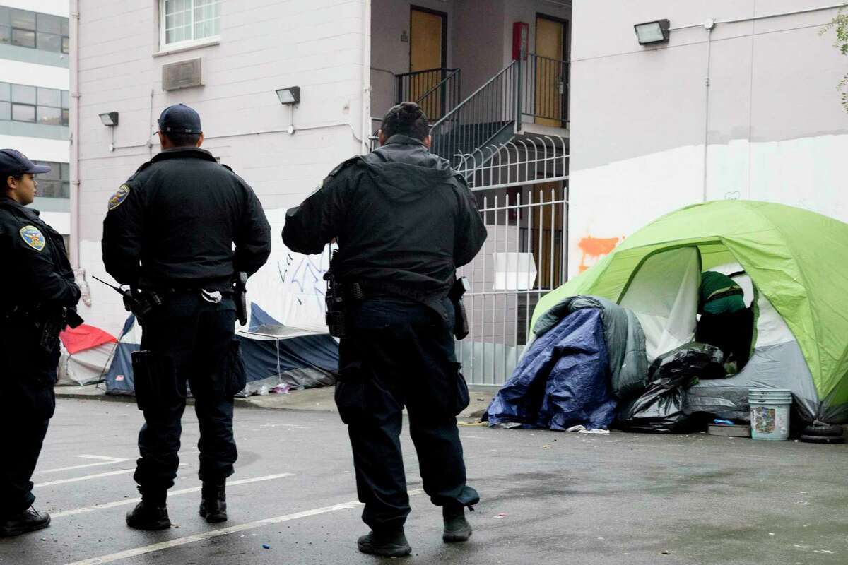 旧金山警察看着人们在公共工程部门沿着柳树街清扫无家可归者的营地时收拾自己的东西。