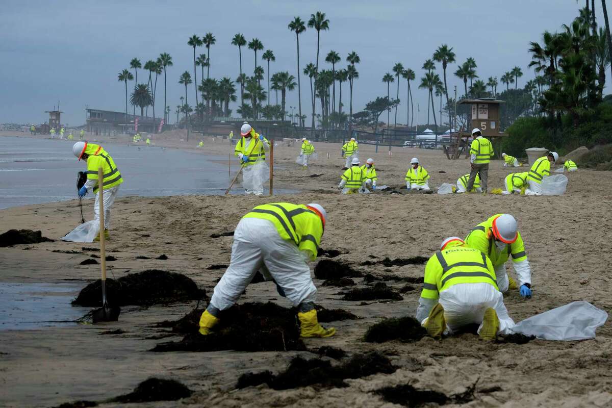 FILE - Workers in protective suits clean the contaminated beach in Corona Del Mar after an oil spill in Newport Beach, Calif., Oct. 7, 2021. According to a federal report released Wednesday, Sept. 28, 2022, oil and natural gas spills from tanker ships and pipelines in U.S. waters dropped dramatically from the last decade of the 1990s to the one from 2010 through 2019.