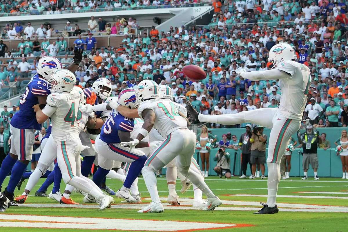 Miami Dolphins punter Thomas Morstead (4) punts the ball into the back of Miami Dolphins wide receiver Trent Sherfield (14) during an NFL football game against the Buffalo Bills, Sunday, September 25, 2022 in Miami Gardens, FL. The Dolphins defeat the Bills 21-19. (Peter Joneleit via AP)