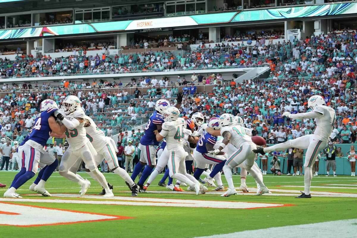 Miami Dolphins punter Thomas Morstead (4) punts the ball into the back of Miami Dolphins wide receiver Trent Sherfield (14) during an NFL football game against the Buffalo Bills, Sunday, September 25, 2022 in Miami Gardens, FL. The Dolphins defeat the Bills 21-19. (Peter Joneleit via AP)