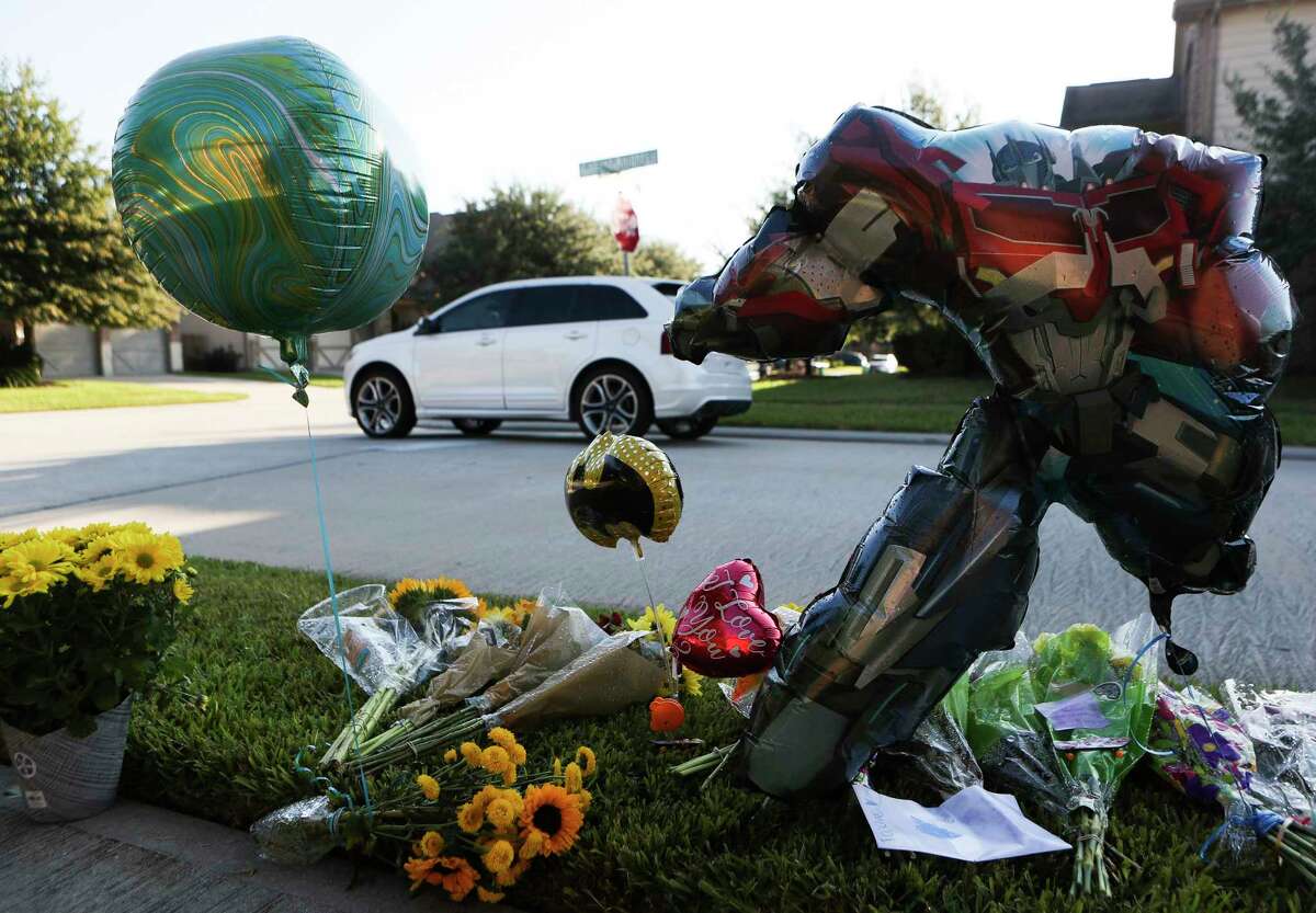 An SUV passes by a small make-shift memorial near the intersection of Gallant Knight Lane and South Kings Mill Lane where an eight-year-old boy was was killed Monday in Kingwood after being hit by an SUV while riding his bike, Wednesday, Sept. 28, 2022.