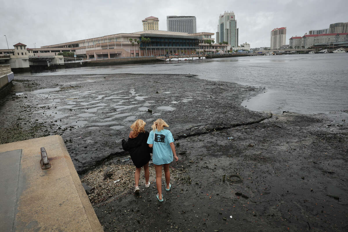 Sisters Angel Disbrow (R) and Selena Disbrow walk along the shore of a receded Tampa Bay as water was pulled out from the bay in advance of the arrival of Hurricane Ian on September 28, 2022 in Tampa, Florida