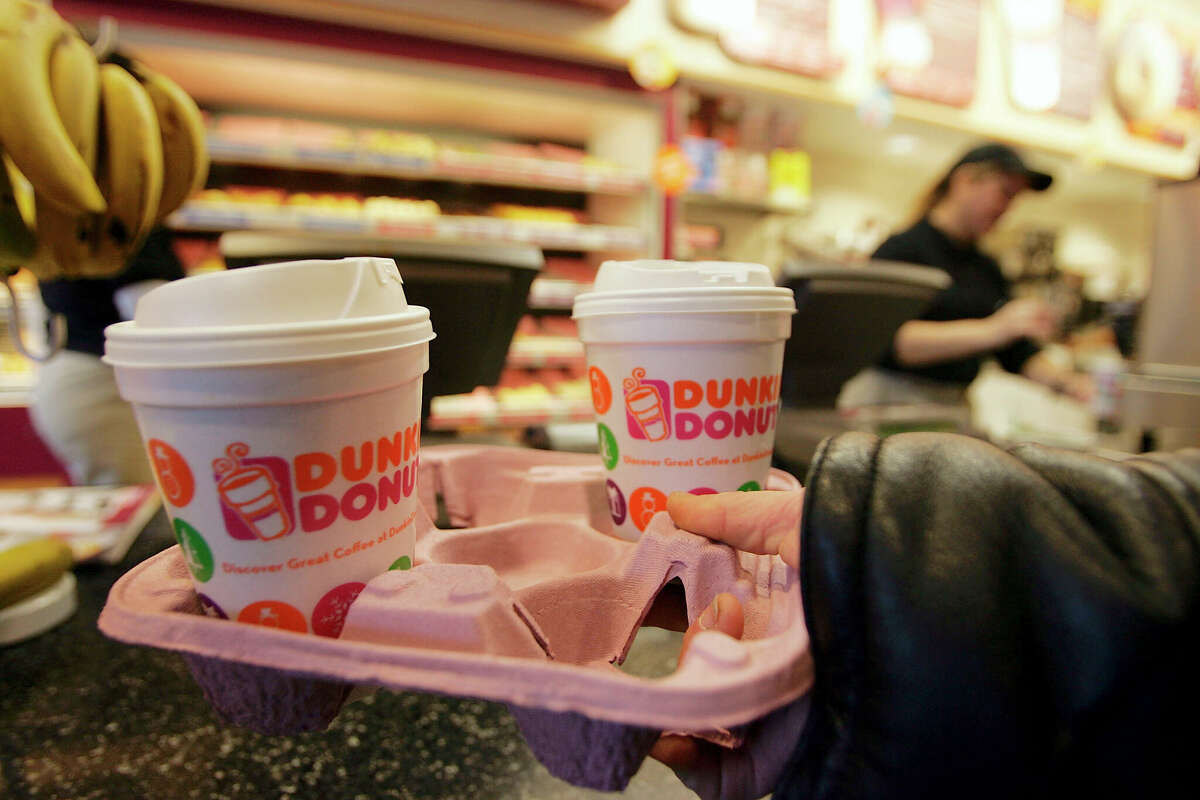 CAMBRIDGE - DECEMBER 12: A customer carries a tray of coffee in a Dunkin' Donuts store December 12, 2005 in Cambridge, Massachusetts. According to reports a group of private equity firms will make a deal to buy Dunkin' Brands from France's Pernod Ricard. The sale would also include the Baskin-Robbins ice cream and Togo?s fast-food chains. (Photo by Joe Raedle/Getty Images)