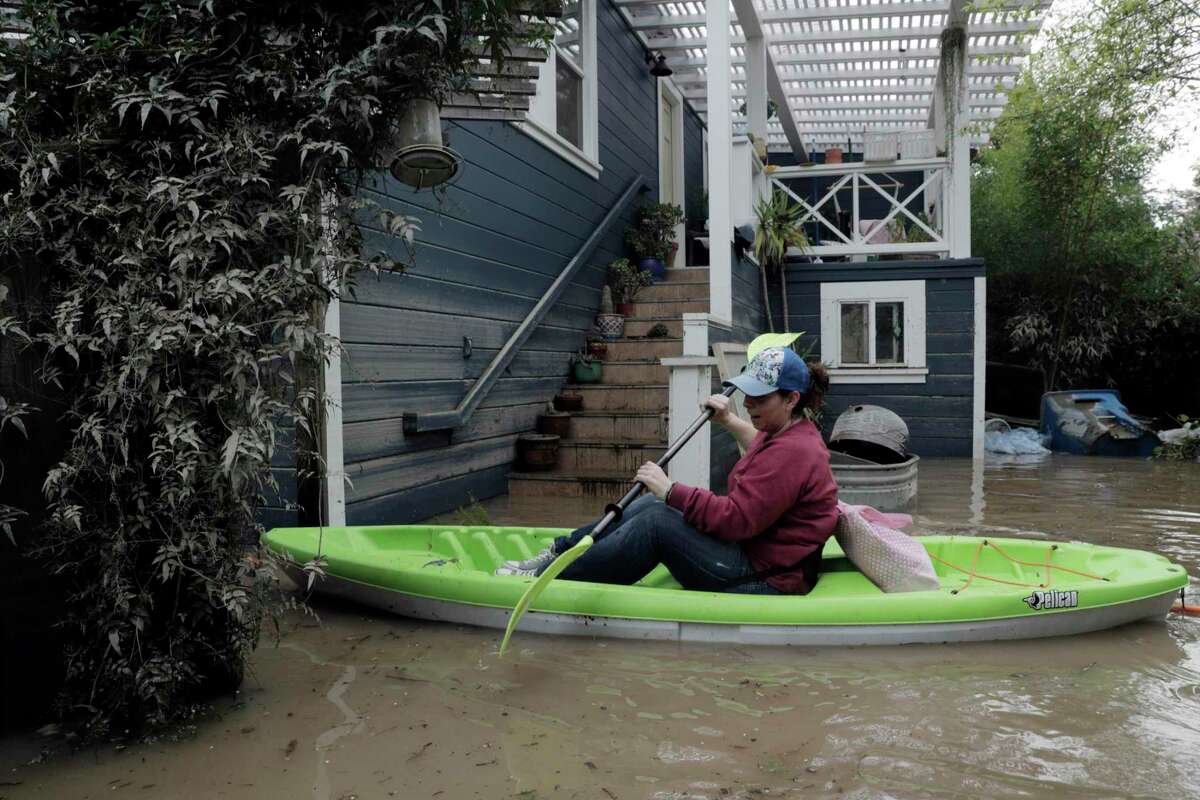Erin Cardiff paddles her way through the gate at her home near River Road in Forestville, Calif., on Thursday, February 28, 2019. The area along the Russian River sustained heavy flooding after an atmospheric river dumped almost 20 inches of rain in two days.