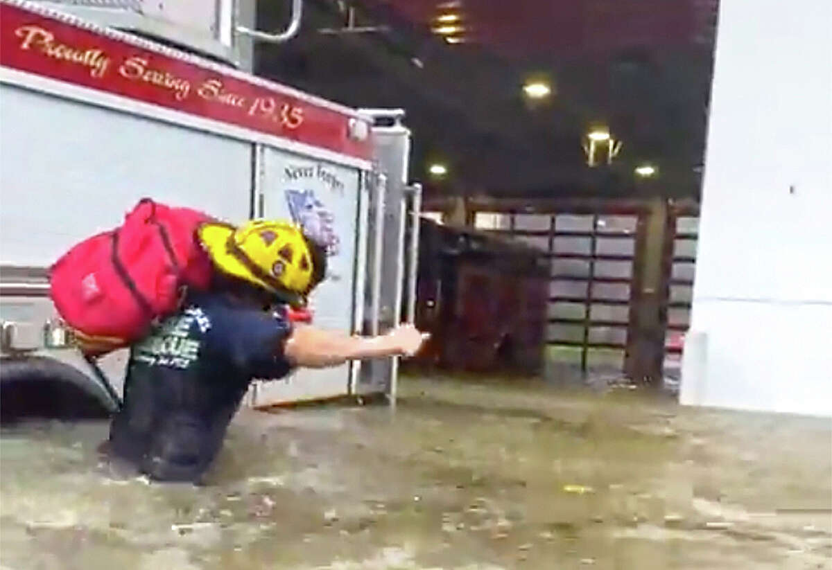 A firefighter carries gear through floodwaters from a storm surge caused by Hurricane Ian in Naples, Florida.