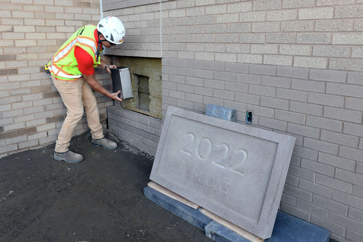 Jae Chu, project manager for Gilbane Construction, puts a time capsule into place during a cornerstone placement ceremony for the new Leo D. Mahoney Arena, currently under construction on the campus of Fairfield University, in Fairfield, Conn. Sept. 28, 2022.
