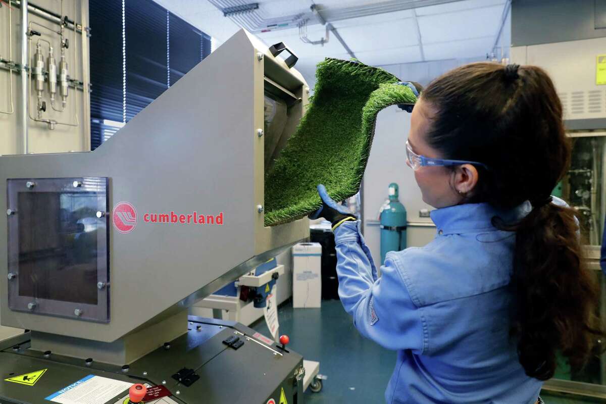 Lab technician Esmeralda Licea loads a piece of sports field turf into a machine that will grind it into little pieces that will be recycled at the Exxon advanced recycling facility, part of the Baytown Technology and Engineering Comples Friday, Sept. 23, 2022 in Baytown, TX.