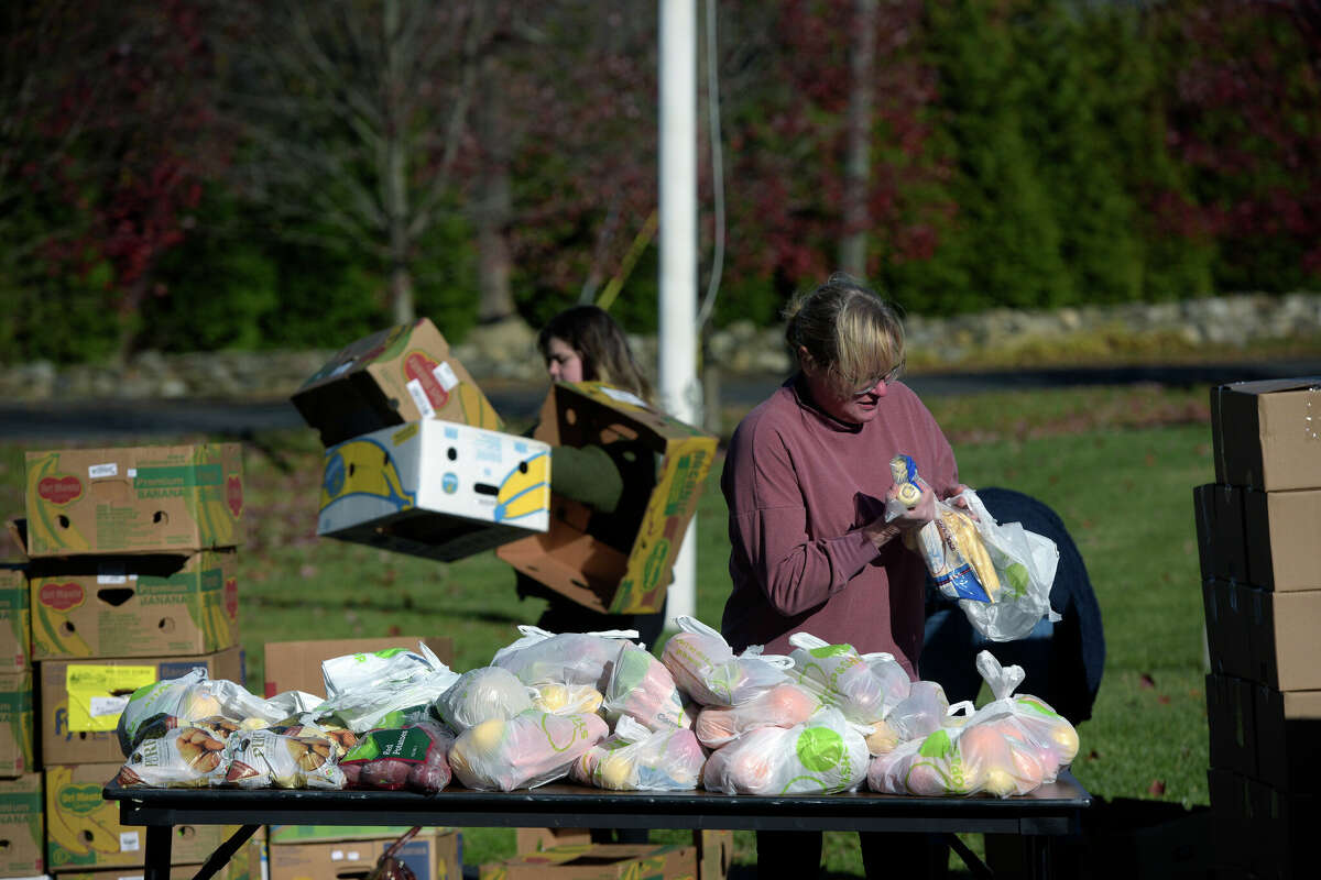 Volunteer C.J. Thomas, of Ridgefield, packs bags of fruit and vegetables at St. Andrew's Church on Friday morning. Food delivered by CT Foodshare was distributed by Ridgefield Social Services on Friday morning, November 19, 2021, Ridgefield, Conn.