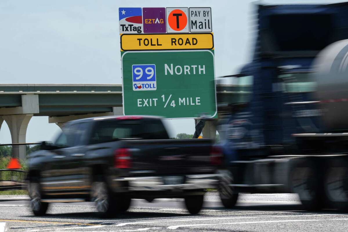 Trucks pass a sign directing drivers to the Grand Parkway on May 18 near Dayton, one day before new segments of the tollway opened. State highway officials are pausing a formula-required increase in toll rates, citing the "unusually high" calculation tied to the consumer price index.