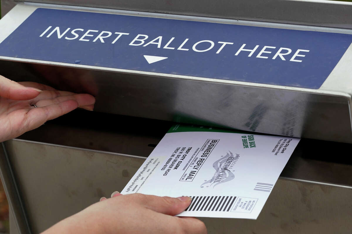 FILE - Nikki Schueller inserts her absentee voter ballot into a drop box in Troy, Michigan, Thursday, Oct. 15, 2020.