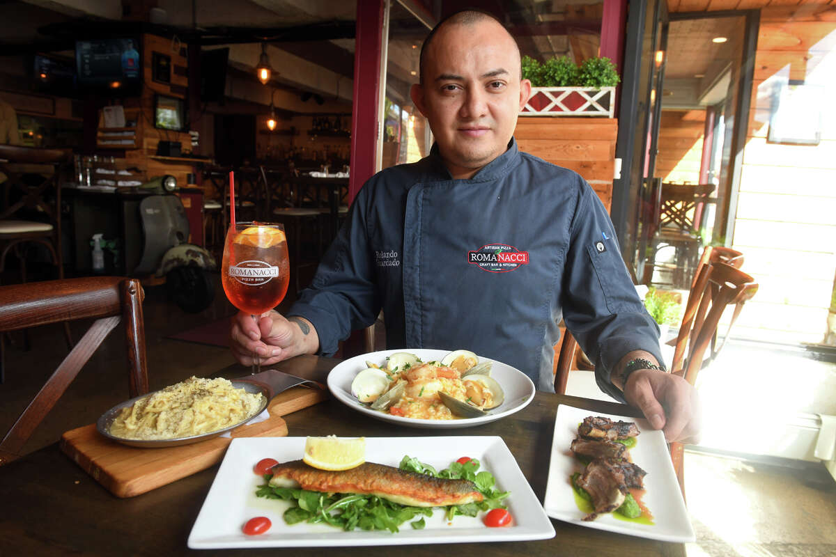 Chef Rolando Guardado poses with a variety of dishes at Romanacci Pizza Bar in Westport, Conn. Sept. 28, 2022. Romanacci will soon be expanding both the dining area and menu at their Westport location.