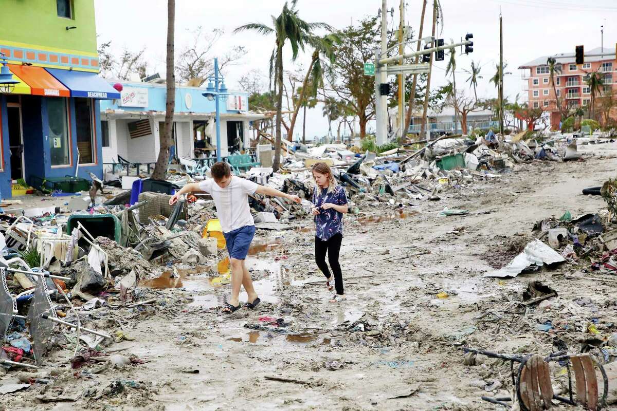 Jake Moses, 19, left, and Heather Jones, 18, of Fort Myers, explore a section of destroyed businesses at Fort Myers Beach, Fla., on Thursday, Sep 29, 2022, following Hurricane Ian. (Douglas R. Clifford/Tampa Bay Times via AP)