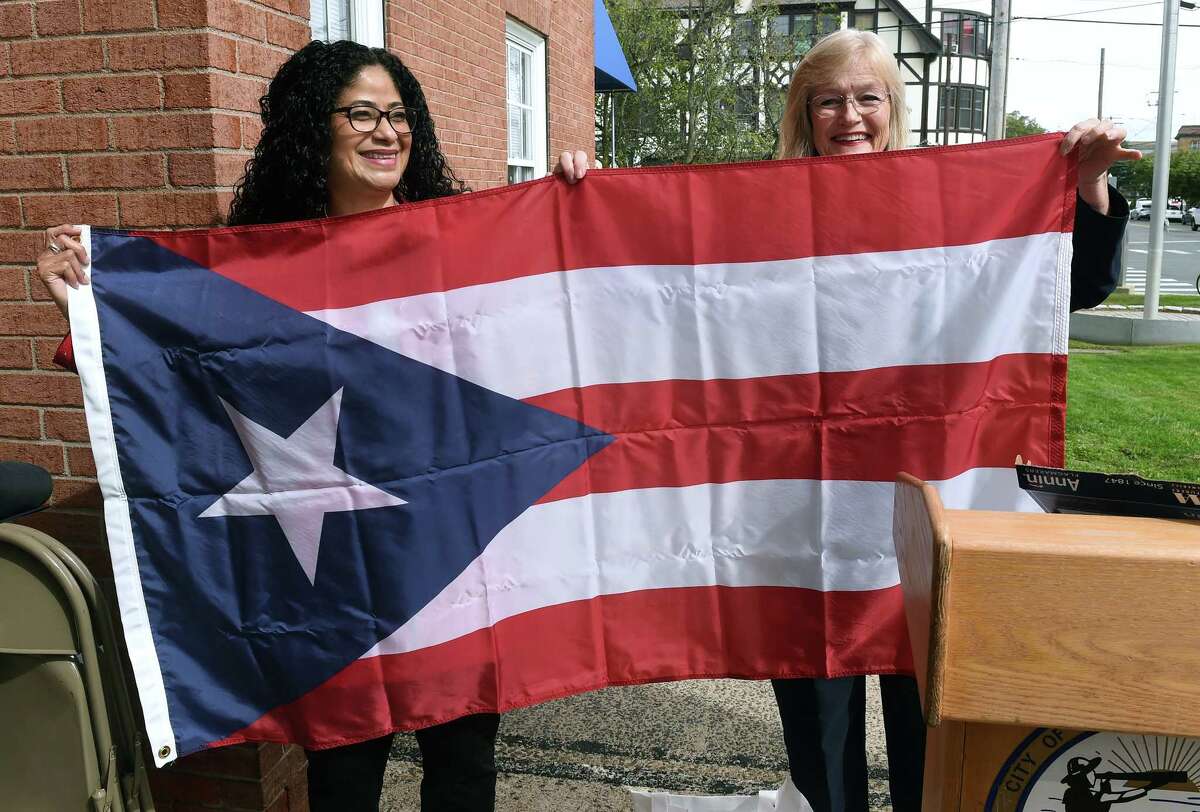 Elsie Encarnacion, left, is presented with a Puerto Rican flag by West Haven Mayor Nancy Rossi during the West Haven 2022 Hispanic Heritage Celebration in front of West Haven City Hall on September 30, 2022.