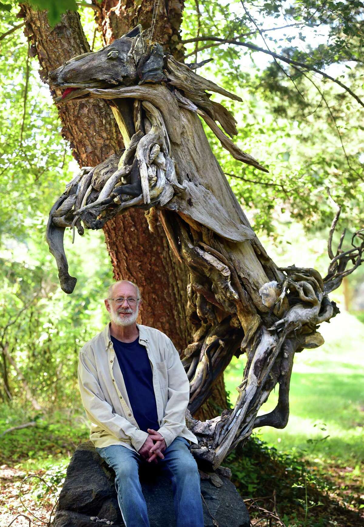 Alan Horwitz is photographed in a Stony Creek park with a horse sculpture, Denali, he made using driftwood .