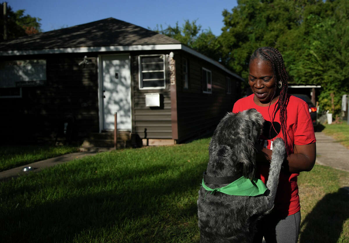 Sandra Edwards plays with her dog, Red, in the front yard of her home across from the Union Pacific rail yard on Wednesday, Sept. 28, 2022 in Houston. Forty-two soil samples collected around the Union Pacific rail yard in the Fifth Ward and Kashmere Gardens tested positive for dioxin, something Edwards, who has been a community advocate and activist regarding the pollutants from the rail yard, has suspected for years.