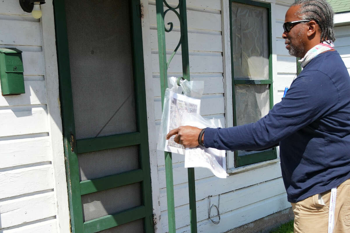 Fifth Ward activist Walter Mallett puts a flyer from the EPA on the porch of a home nearwhere testing found dioxins in samples stemming from the Union Pacific rail yard on Thursday, Sept. 29, 2022 in Houston.
