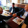 Bob Stefanowski, the Republican candidate for governor, right, greets Greenwich resident Bob Elmo, during a stop at The Cos Cobber to meet and greet diners in the Cos Cob section of Greenwich, Conn., on Wednesday September 28, 2022. Seated with Elmo is his brother-in-law German Escobar. Virginia's Governor Glenn Youngkin also made the stop with Stefanowski to drum up support for his campaign.