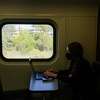 Caitlin Kamm, Head of People Growth at Envoy, works on her laptop while commuting home on CalTrain.