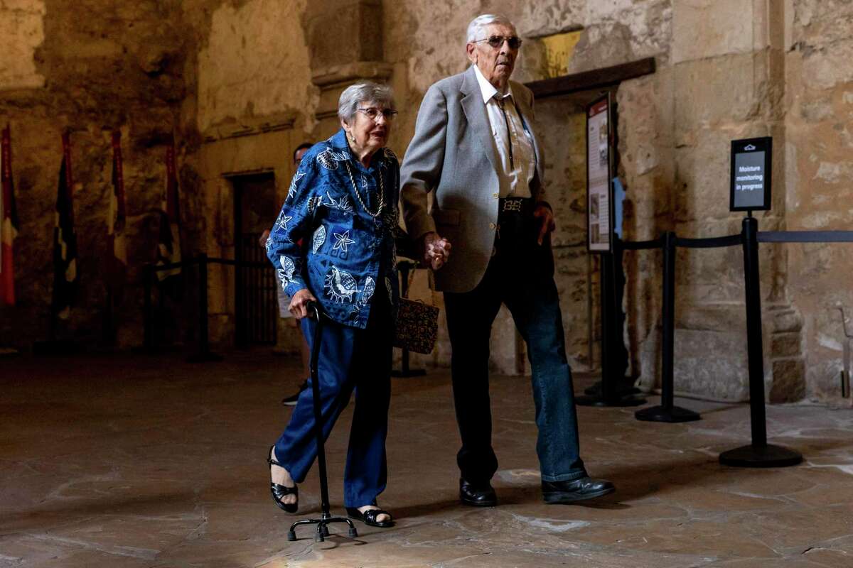 Longtime Bexar County collectors Louise and Donald Yena walk through the Alamo Church on Friday.