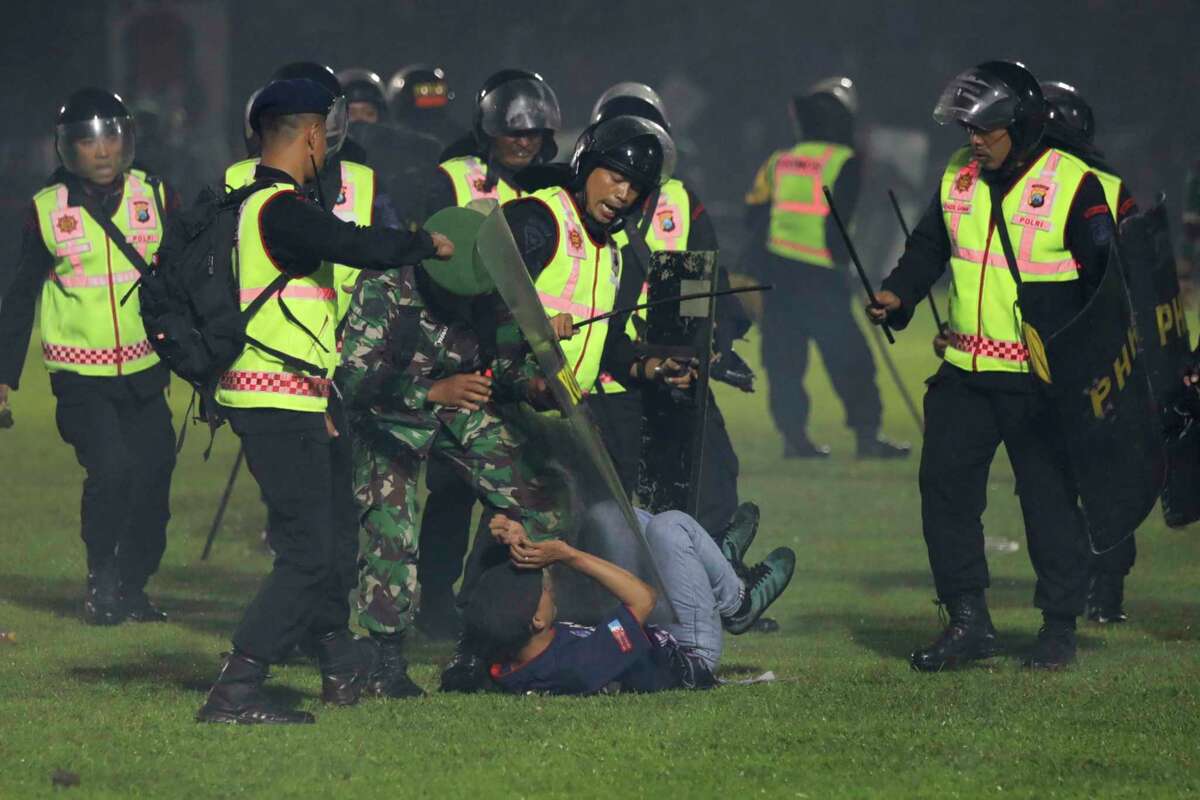 Security officers detain a fan during a clash between supporters of two Indonesian soccer teams at Kanjuruhan Stadium in Malang, East Java, Indonesia, Saturday, Oct. 1, 2022. Panic following police actions left over 100 dead, mostly trampled to death, police said Sunday.
