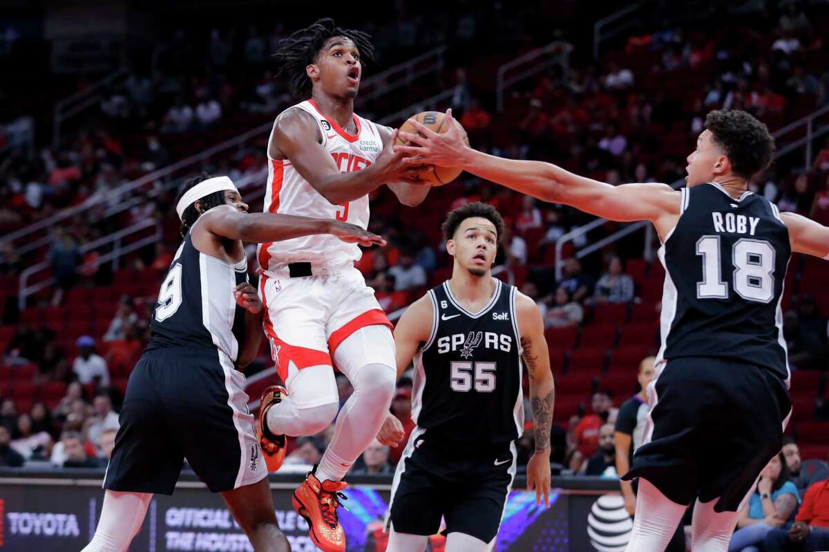 Houston Rockets guard Josh Christopher, top, drives up a shot between San Antonio Spurs forward Alize Johnson, left, guard Jordan Hall (55) and forward Isaiah Roby (18) during the second half of an NBA preseason basketball game Sunday, Oct. 2, 2022, in Houston. (AP Photo/Michael Wyke)