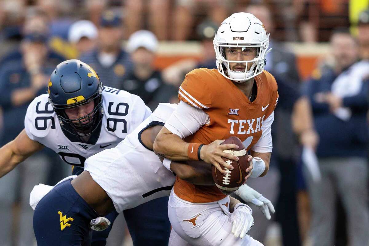 Texas quarterback Hudson Card (1) looks for a receiver as he is pressured by West Virginia defensive lineman Edward Vesterinen (96) and linebacker Jasir Cox during the first half of an NCAA college football game Saturday, Oct. 1, 2022, in Austin, Texas.