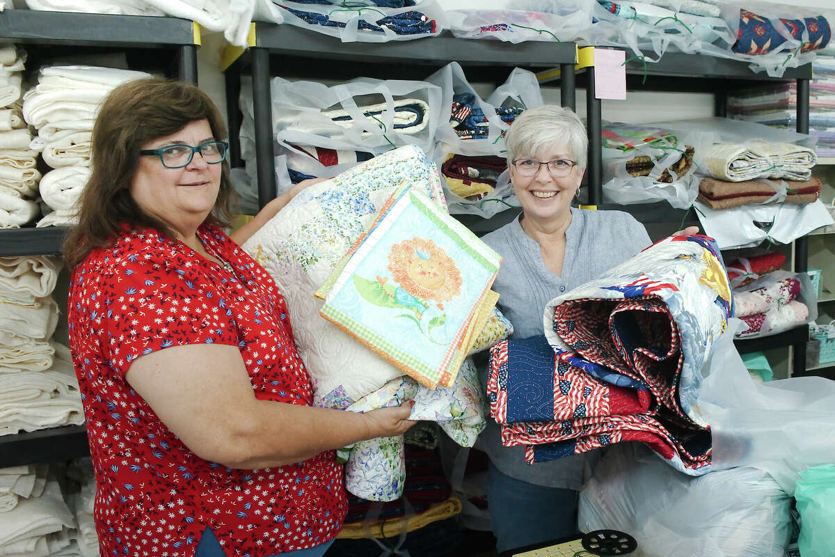 Sheryl Hayslip-Bahena and Mitzi Leatherman hold donated quilts to be distributed to veterans.