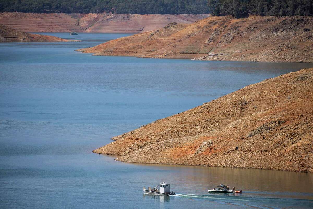 Boats are seen in Shasta Lake as the shoreline is exposed by low water levels on Aug. 26, 2022.