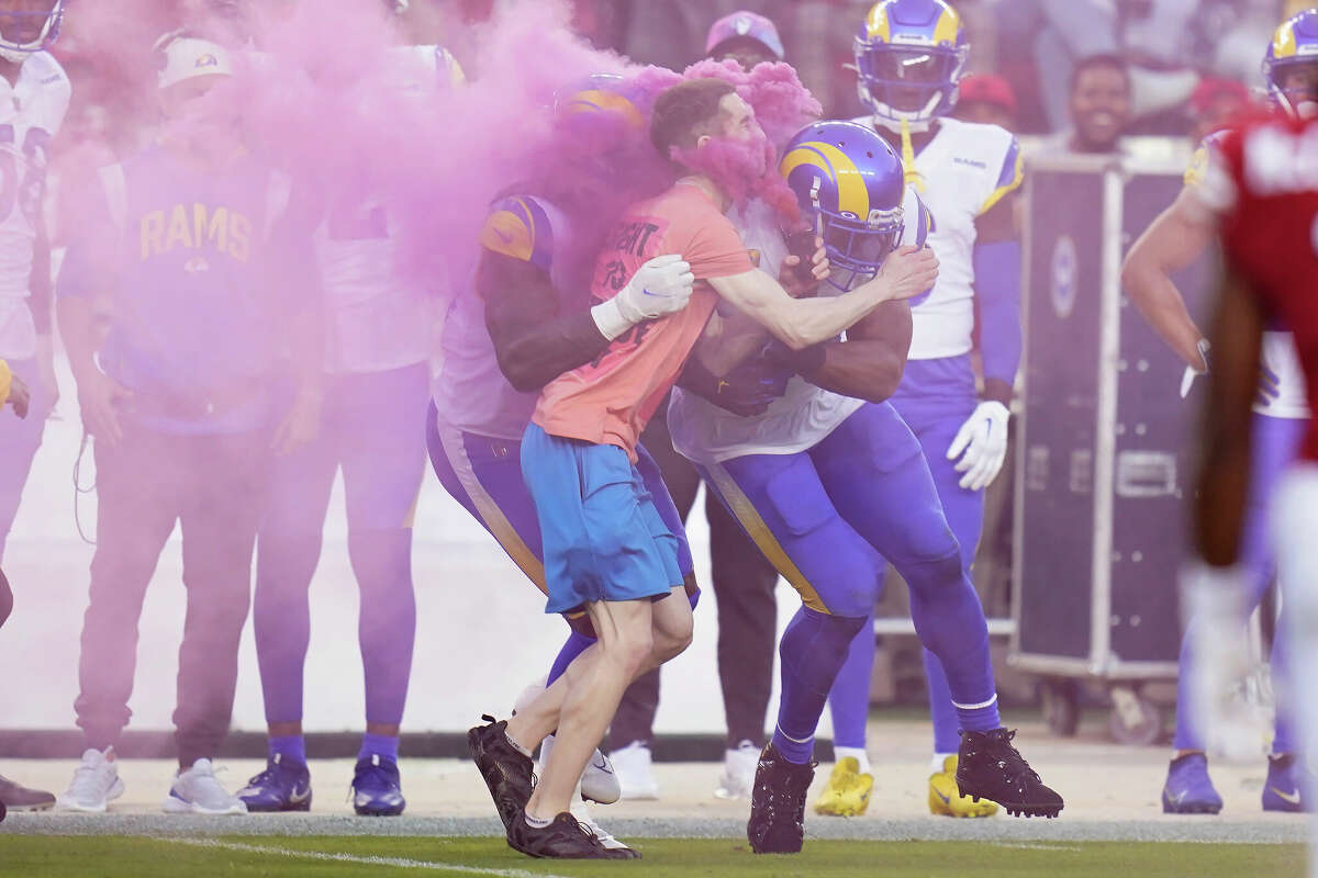 A protester is hit by Los Angeles Rams defensive end Takkarist McKinley, middle left, and linebacker Bobby Wagner during the first half of an NFL football game between the San Francisco 49ers and the Rams in Santa Clara, Calif., Monday, Oct. 3, 2022. (AP Photo/Godofredo A. VÃ¡squez)