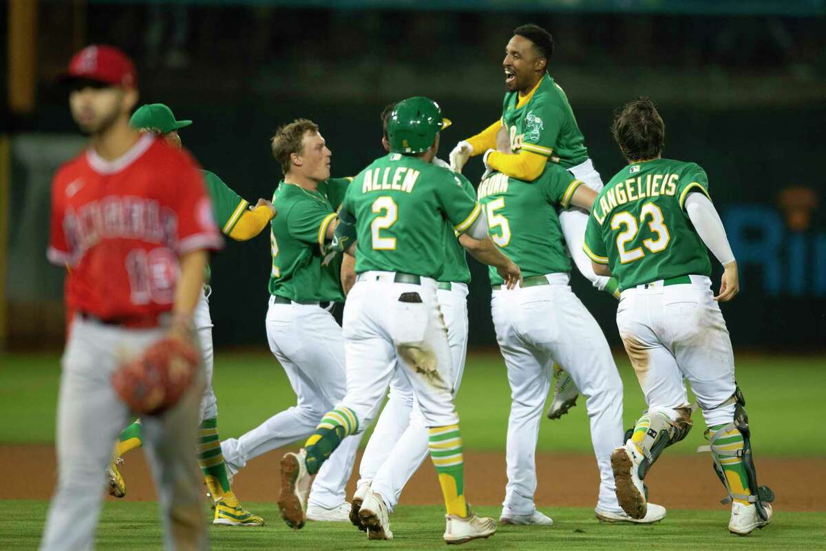 Oakland Athletics pinch hitter Tony Kemp, top, is mobbed by his teammates after driving in the winning run against the Los Angeles Angels during the tenth inning of a baseball game, Monday, Oct. 3, 2022, in Oakland, Calif. The A's defeated the Angels 5-4.(AP Photo/D. Ross Cameron)