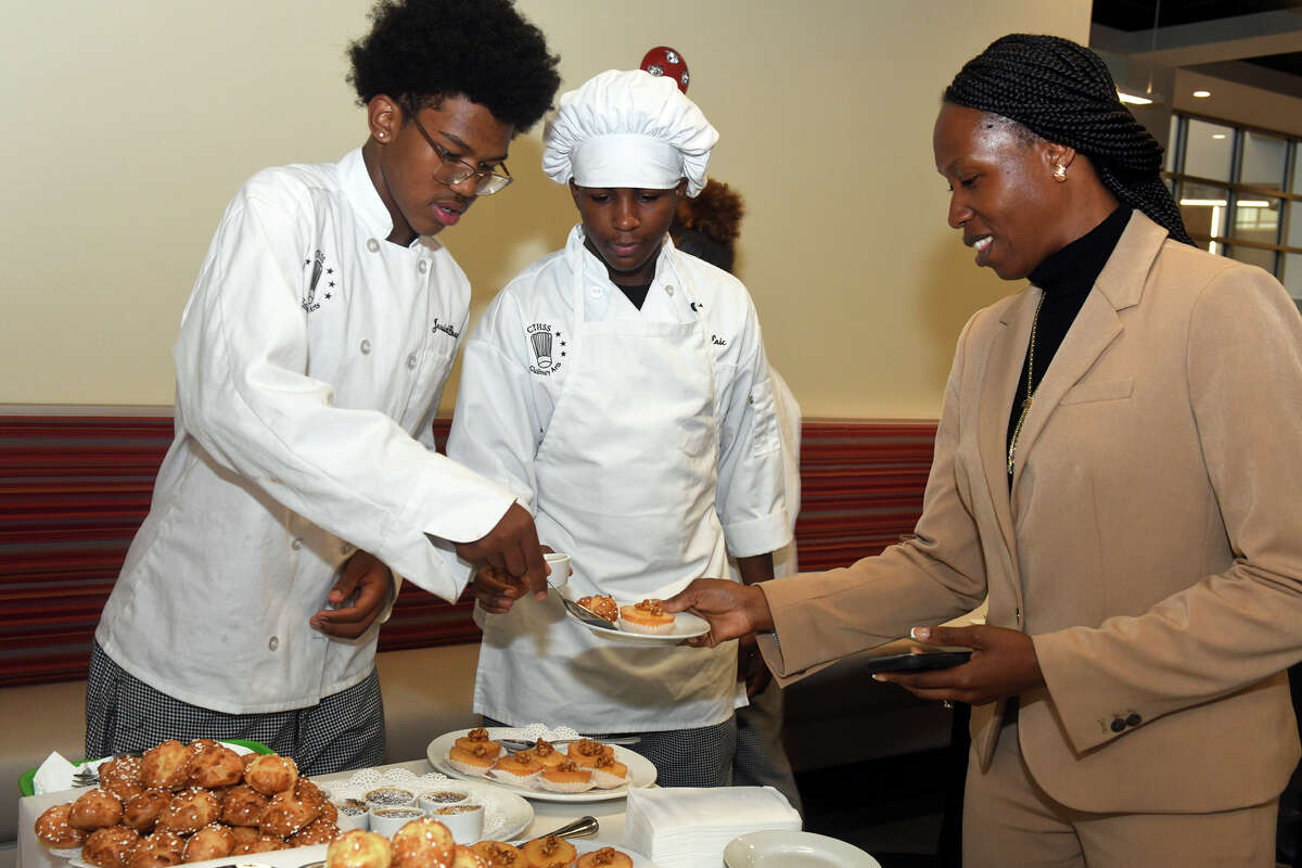 Culinary students Jessiah Brown, left, of Derby, and Eric Richardson, of New Haven, serve pastries to guests during a reception following a ribbon-cutting ceremony for the new Platt Technical High School, in Milford, Conn. Oct. 4, 2022.