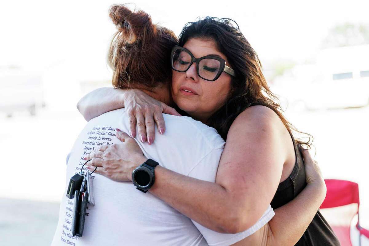 Nikki Cross, left, receives a hug from Christina Delgado of Santa Fe, Texas, who visited the protest group Saturday at the Uvalde CISD administration building. Delgado, a human rights advocate whose own community was rocked by a school shooting in 2018, showed up to offer support to the Uvalde families.