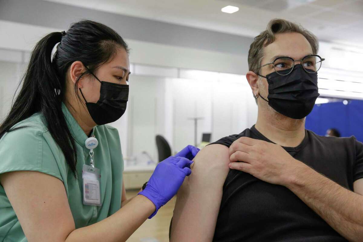 Kaiser nurse Marilyn Antonio, left, puts a bandage on Ted Naifeh, right, from San Francisco, after a Moderna booster shot at Kaiser Permanente City Center Vaccine Clinic in San Francisco on Sept. 22, 2022.