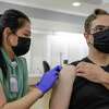 Kaiser nurse Marilyn Antonio, left, puts a bandage on Ted Naifeh, right, from San Francisco, after a Moderna booster shot at Kaiser Permanente City Center Vaccine Clinic in San Francisco on Sept. 22, 2022.