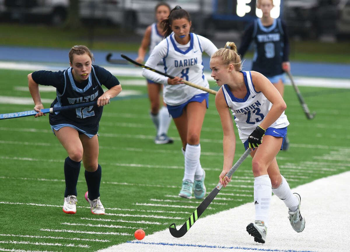 Darien's Blake Wilks (23) brings the ball up the sidelines during a field hockey game against Wilton in Darien on Tuesday, Oct. 4, 2022.