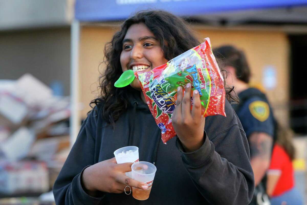 Sergio Castro, age 14, shows off his haul of free snacks to his friends during the annual National Night Out at the Burnett Bayland Park location Tuesday, Oct. 4, 2022 in Houston, TX.