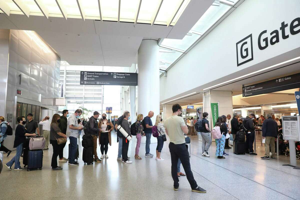 People stream beyond the queue line created by stanchions at a security checkpoint into the International Terminal at San Francisco International Airport in San Francisco, Calif.