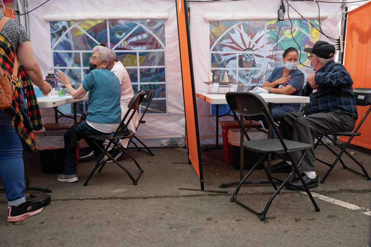 丈夫和妻子玛丽亚(左)和福斯蒂诺·萨拉查(右)准备接受他们的Covid-19助推器，而女儿玛丽亚·瓜达卢佩·萨拉查(左)在那里协助社区测试和疫苗接种诊所，卫生联盟/Unidos en Salud于2022年9月23日星期五在加利福尼亚州旧金山的教会区出现。