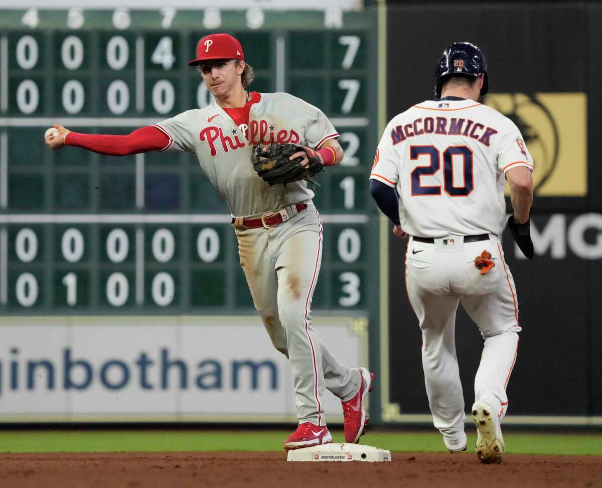 Philadelphia Phillies shortstop Bryson Stott (5) makes the throw to first base after tagging Houston Astros Chas McCormick (20) out as Christian Vazquez ground into a double play to end the seventh inning of an MLB baseball game at Minute Maid Park on Tuesday, Oct. 4, 2022 in Houston.