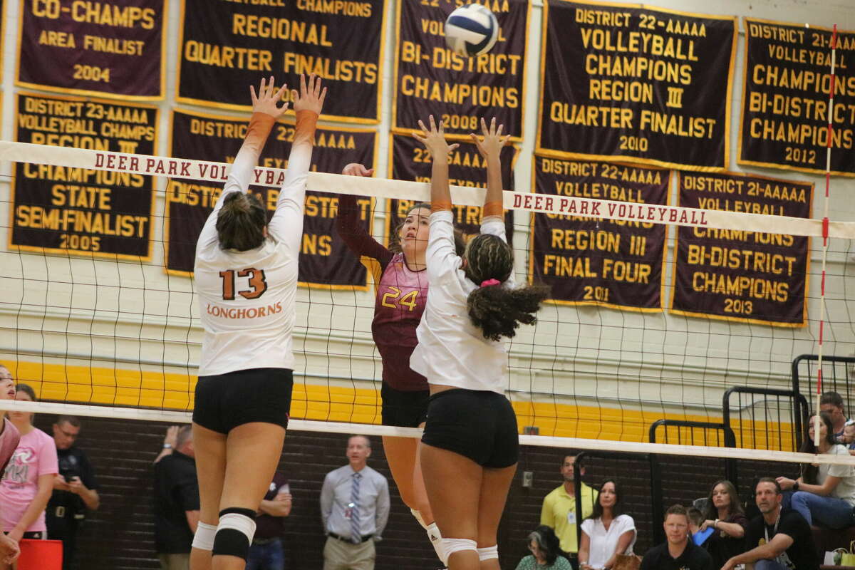 A pair of Dobie potential blockers at the net force Cayley Hanson (24) to go too long on this kill attempt in Game 1 Tuesday night.