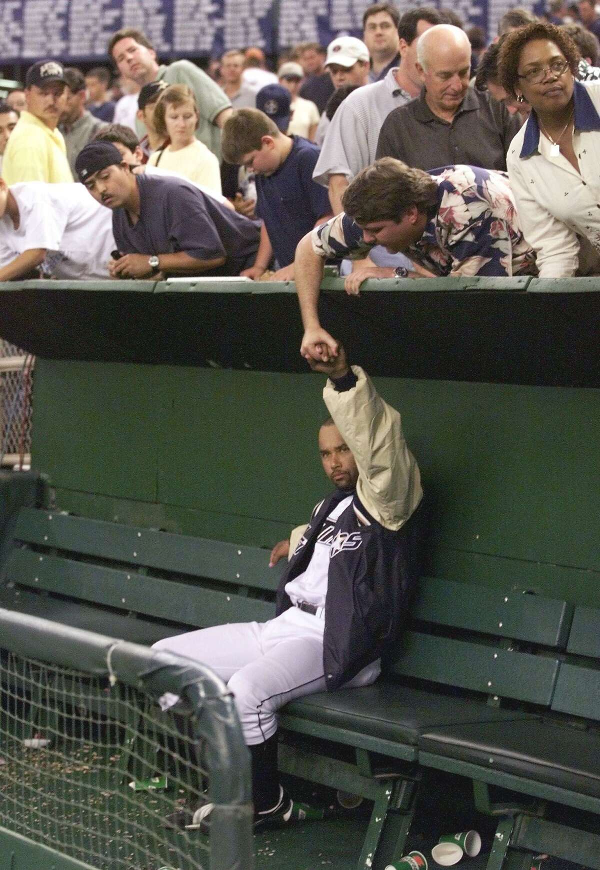 A fan reaches over the dugout to shake hands with pitcher Jose Lima of the Houston Astros after game four of the National League Divisional Series October 9, 1999.
