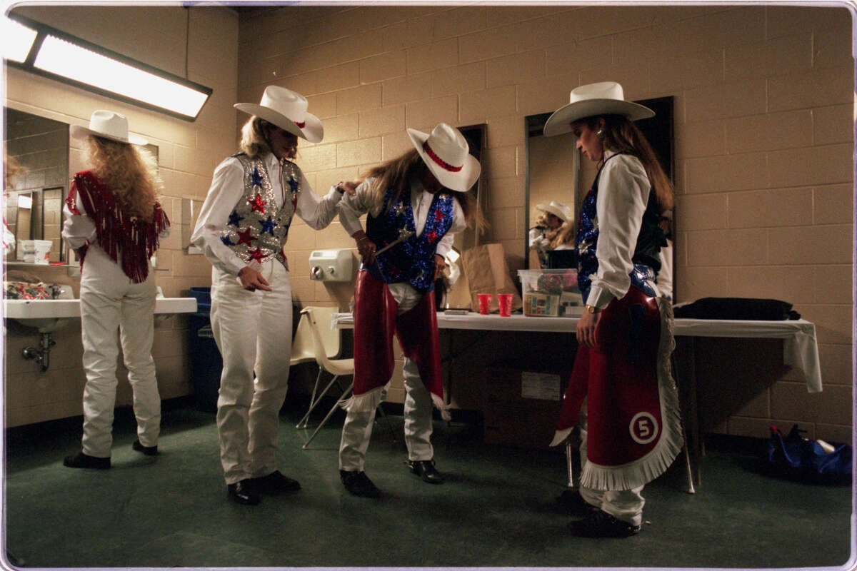 1998: The cowgirls who perform each night at the rodeo. Pam Oppelt, left, of Houston helps Michelle Hunt of Mexia with her chaps as Tonya Laminack of Houston checks to make sure everyone is properly uniformed.