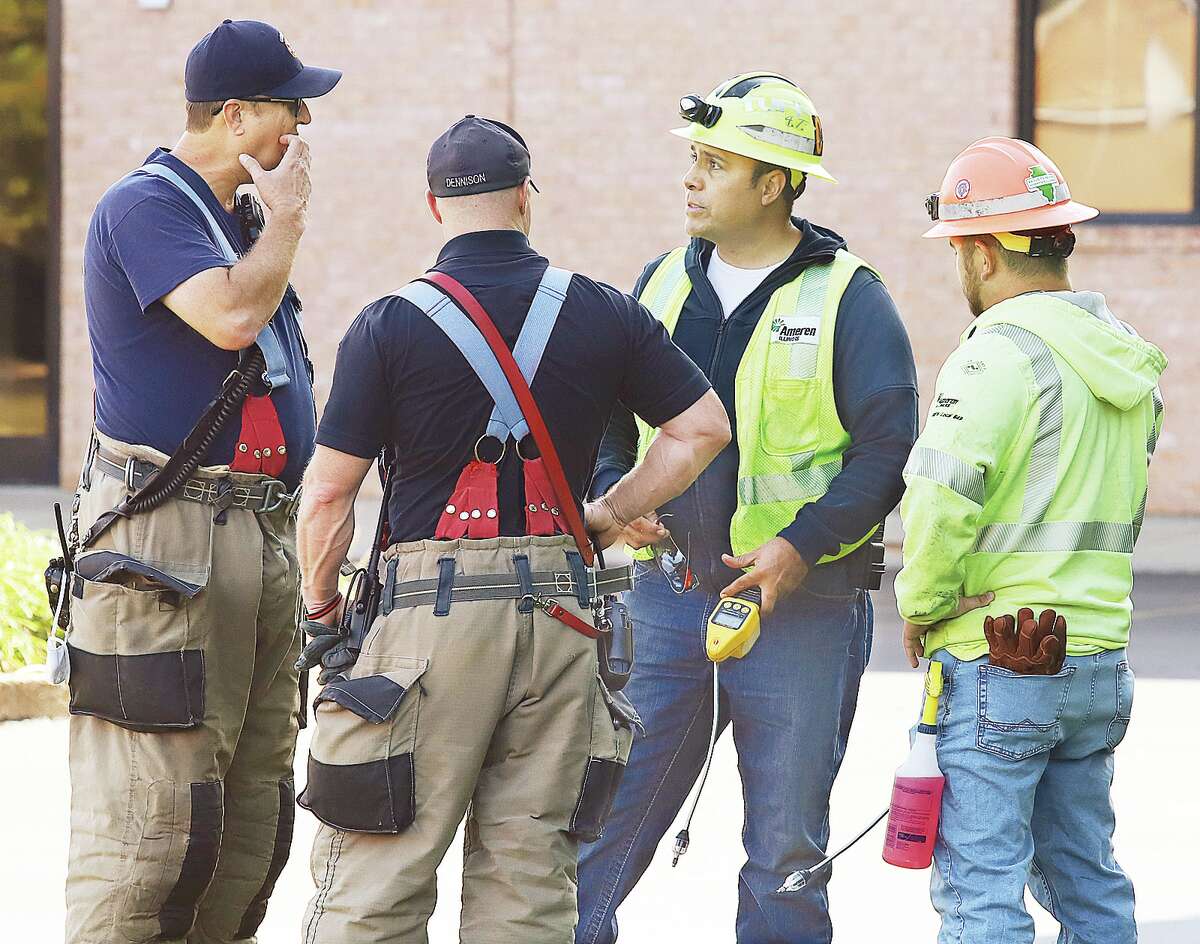 John Badman|The Telegraph Godfrey firefighters confer with Ameren Gas Division workers behind the Evangelical Schools Wednesday during a gas leak.
