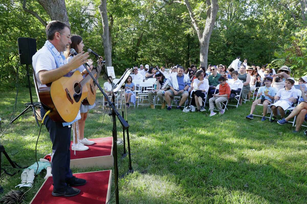 Rabbi Ranon Teller and his daughter, Nava, lead songs at a service Wednesday during the observance of Yom Kippur by members of Congregation Brith Shalom at the Nature Discover Center.