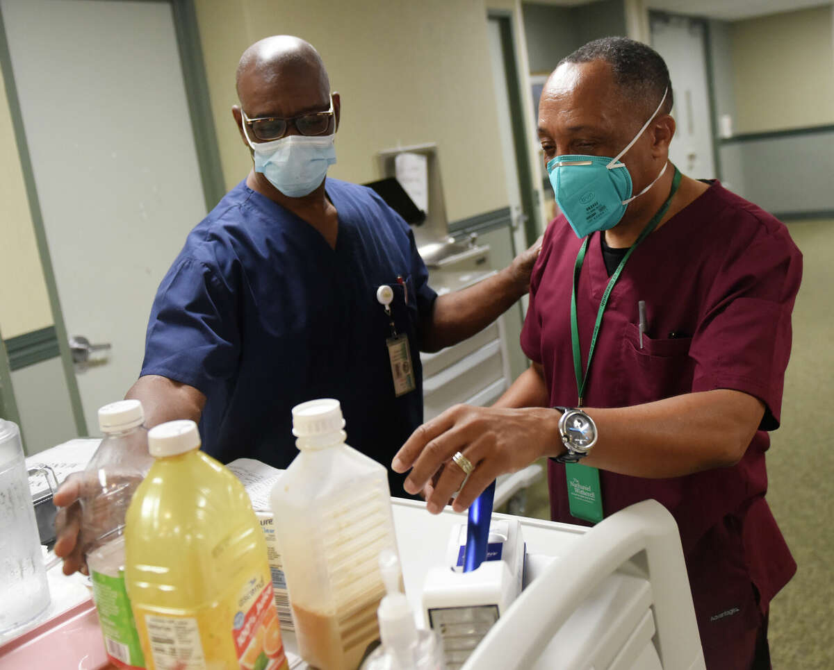 Altiery Telo, LPN, left, and Francklin Fequiere, LPN, work at the nurses station at Nathaniel Witherell nursing and rehabilitation center in Greenwich, Conn. Wednesday, Oct. 5, 2022.