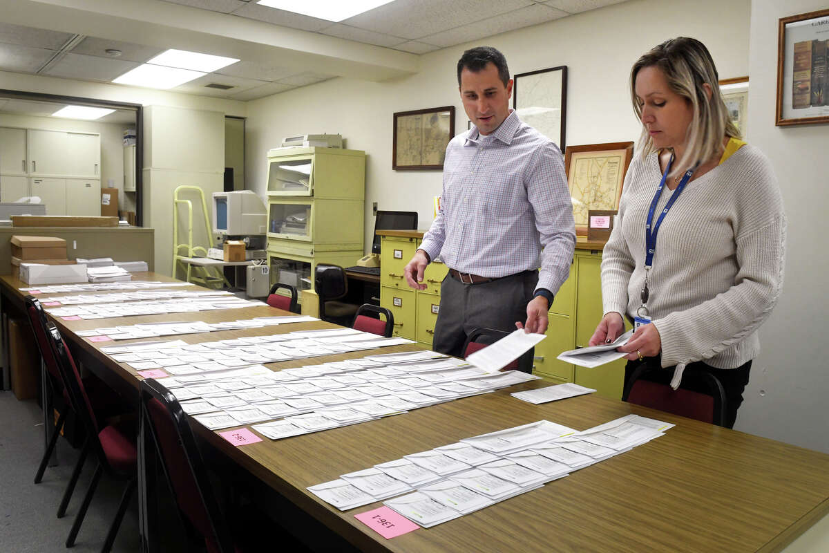 Town Clerk Jeffrey Dunkerton and Assistant Town Clerk Tatiana Plachi look over absentee ballots before they are mailed out in Westport, Conn. Oct. 5, 2022.